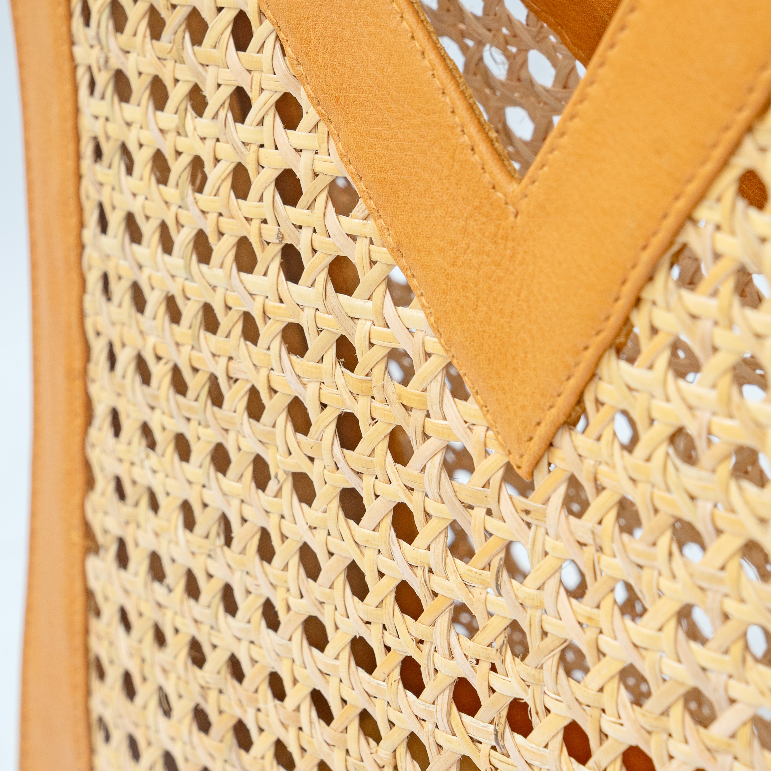 Detail up close view of tan leather and cane webbing rattan top handle tote handbag