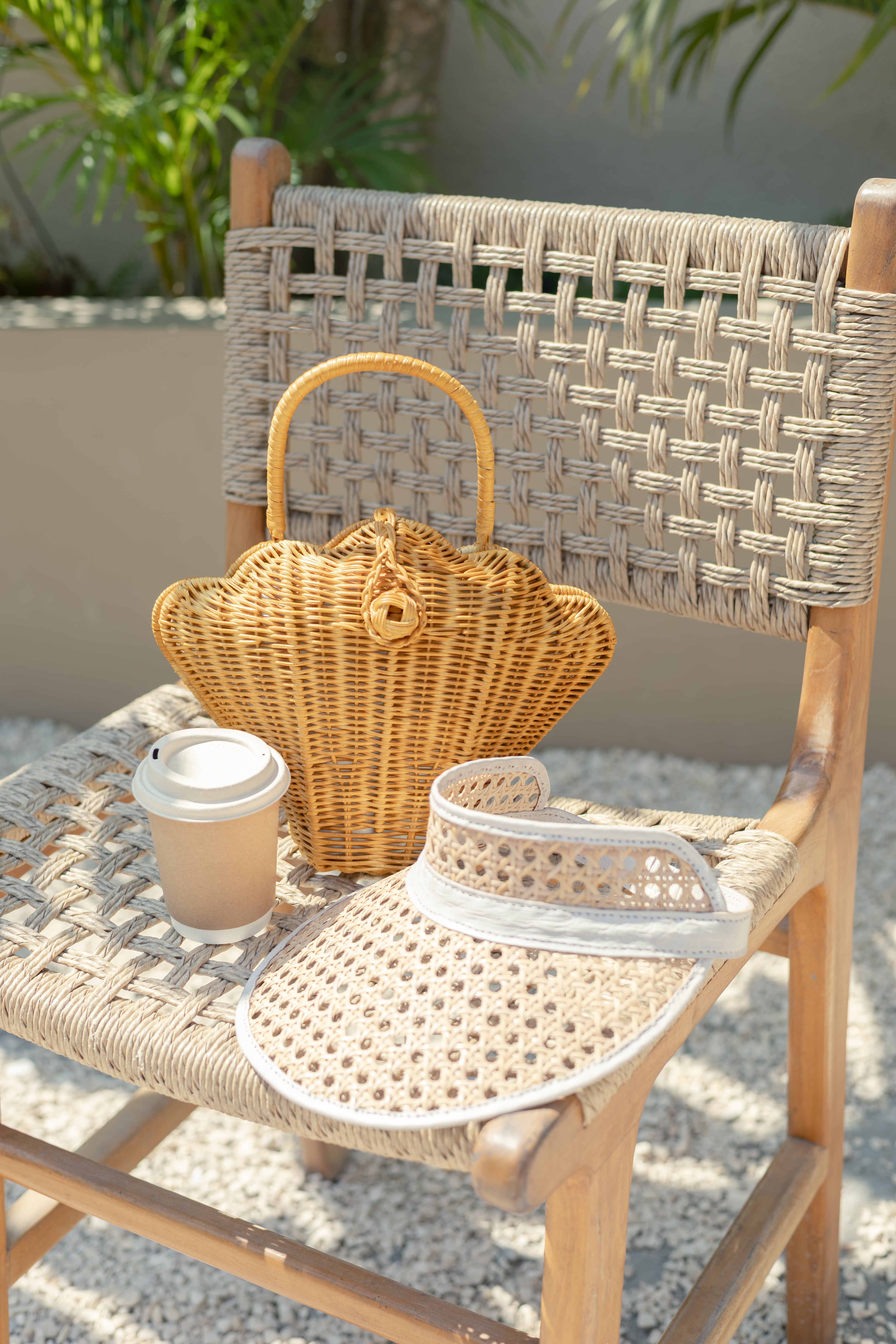 Seashell-shaped woven rattan handbag styled for a luxury resort vacation.