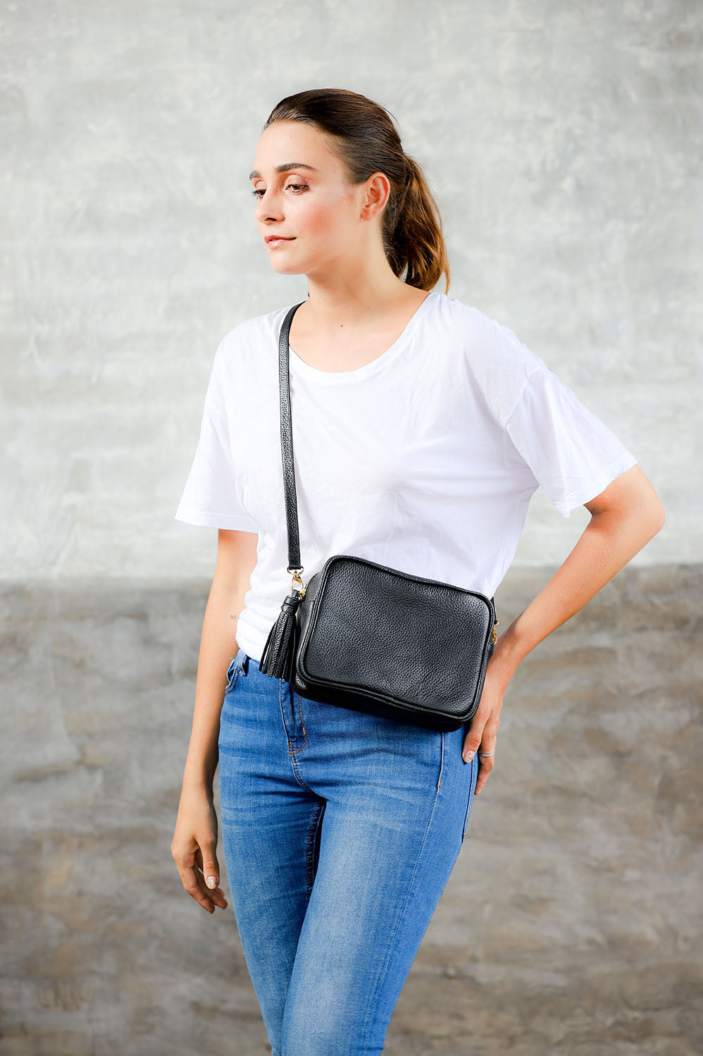 Model wearing black cowhide pebbled leather crossbody bag