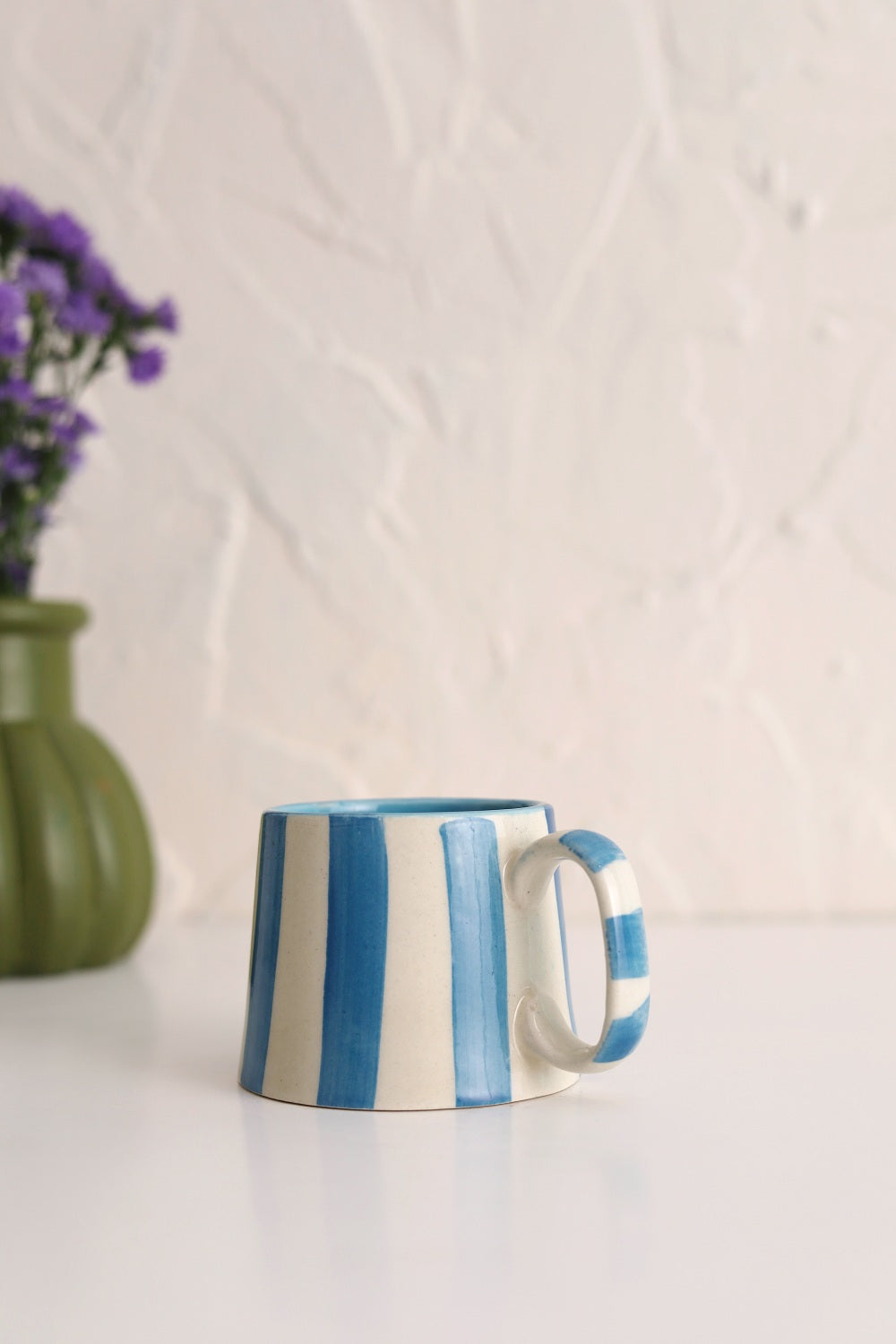 Blue and white striped mug on a white surface with a light background