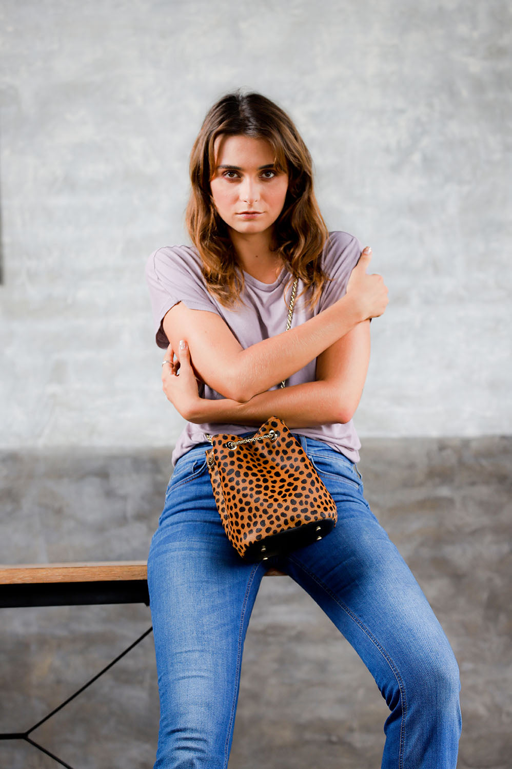model sitting wearing crossbody drawstring leopard handbag