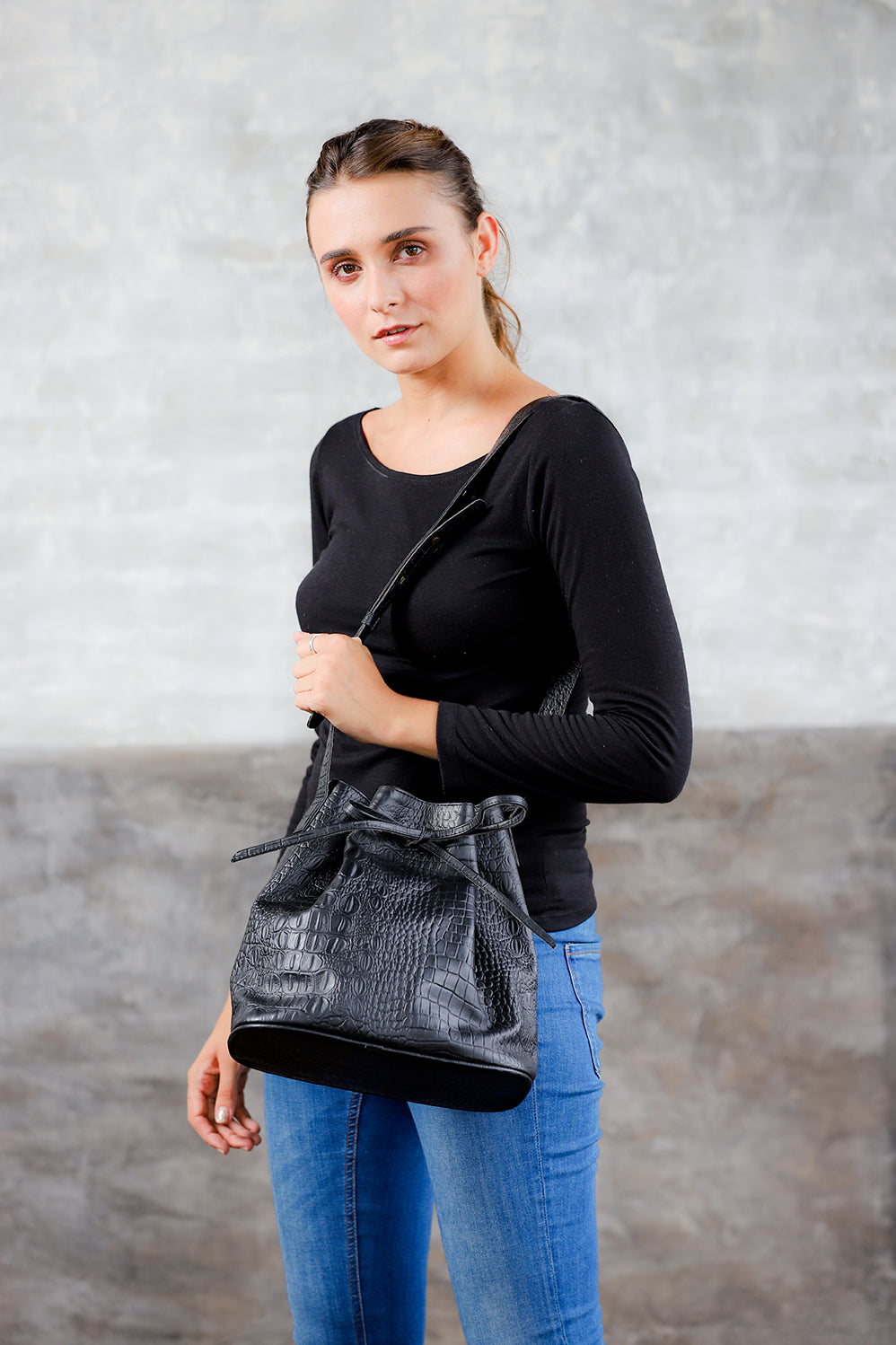 Front view  model wearing black crossbody crocodile embossed leather bucket bag