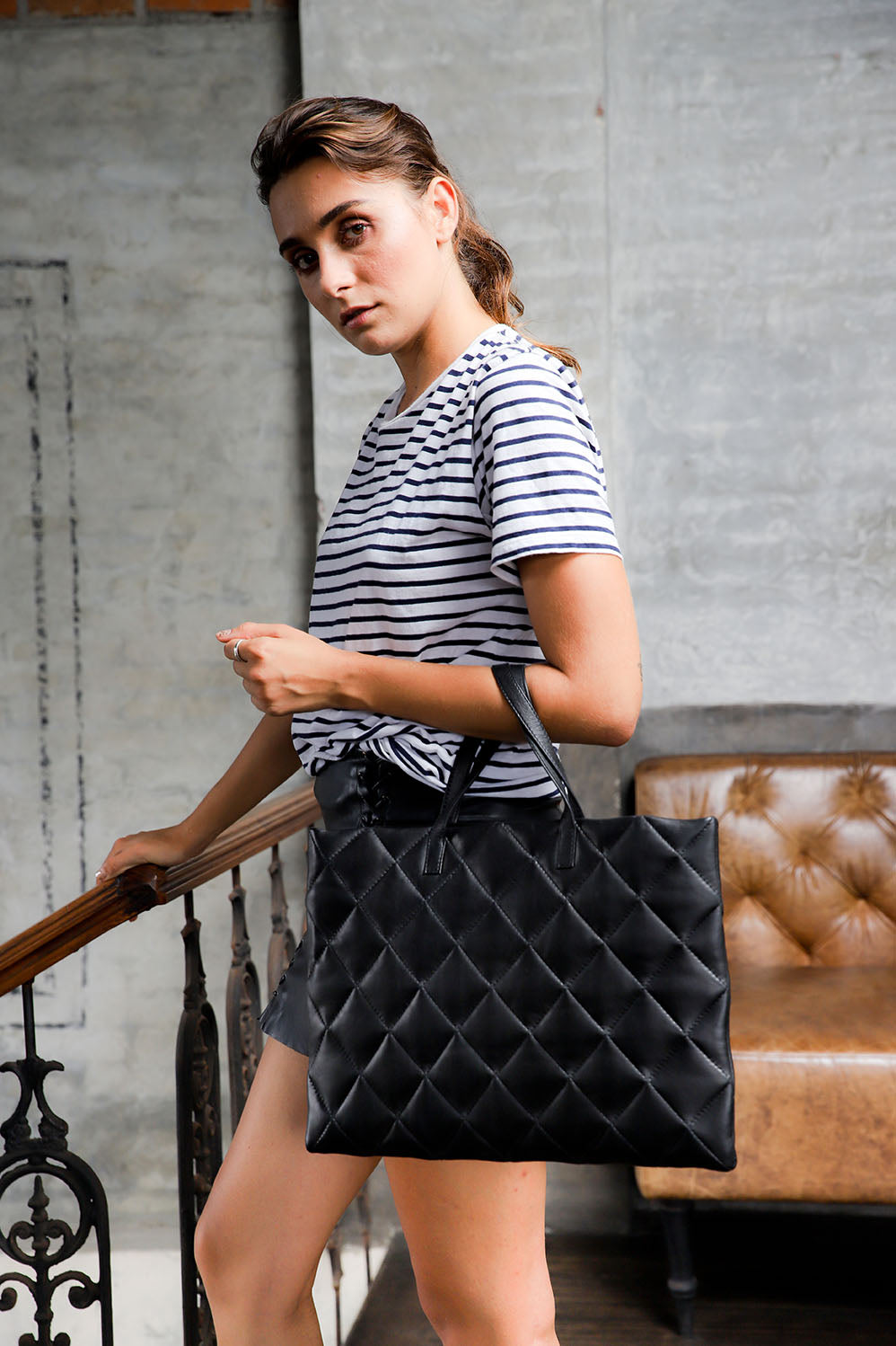 model wearing quilted black leather tote bag