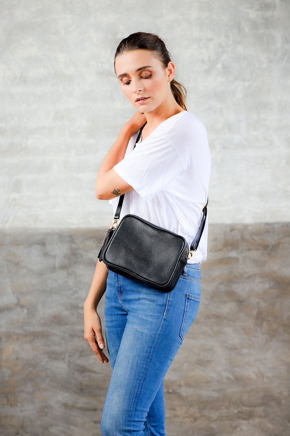 model wearing side view black pebbled cowhide leather camera bag